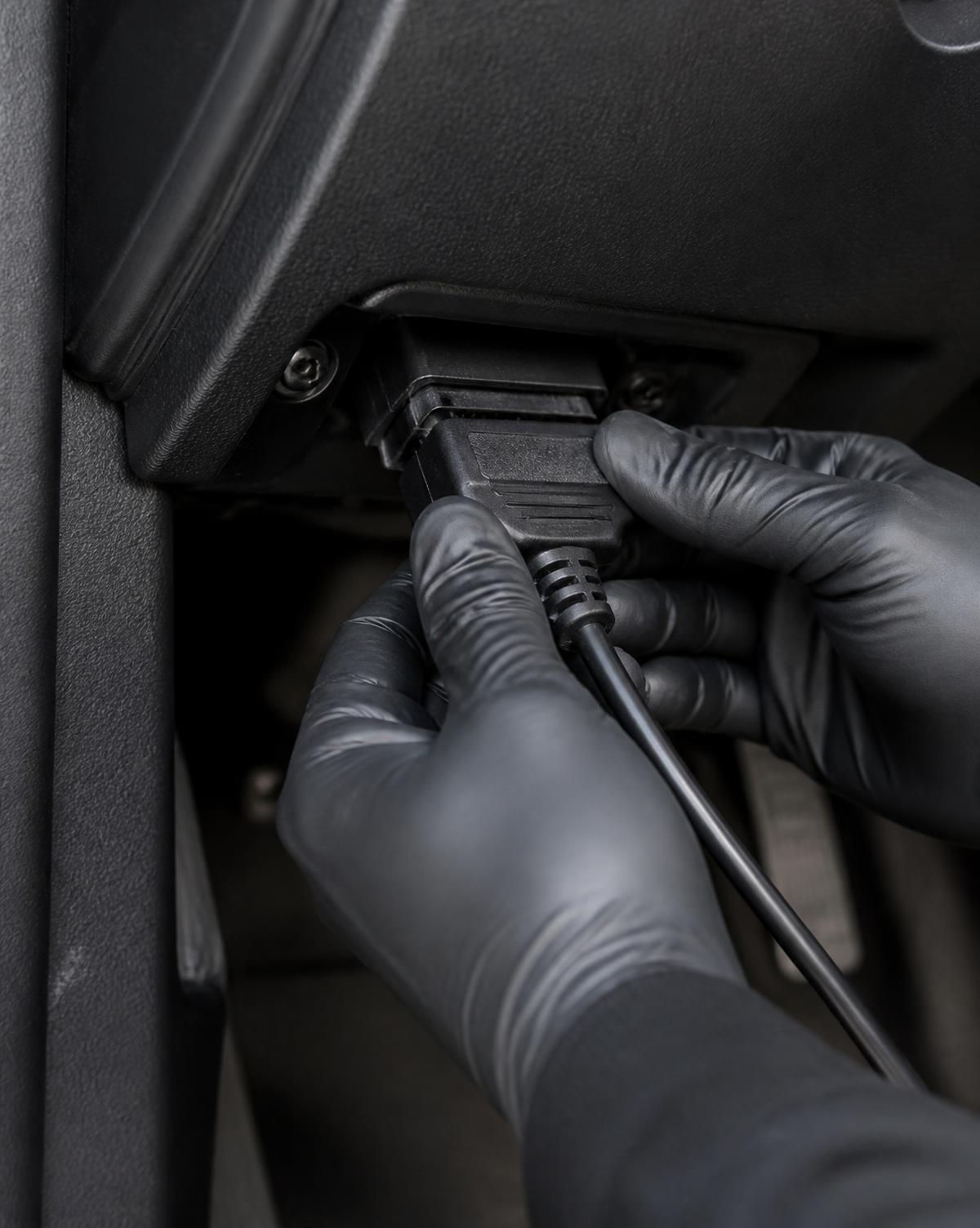 A technician connecting a diagnostic cable to a vehicle's OBD port